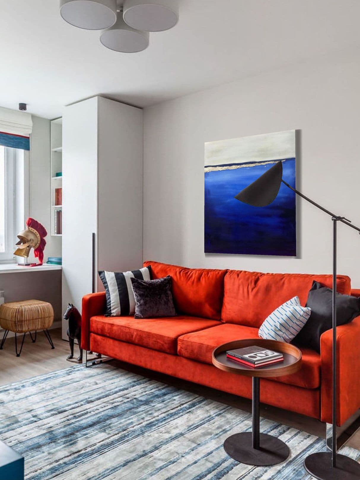 синяя картина в интерьере с красным диваном