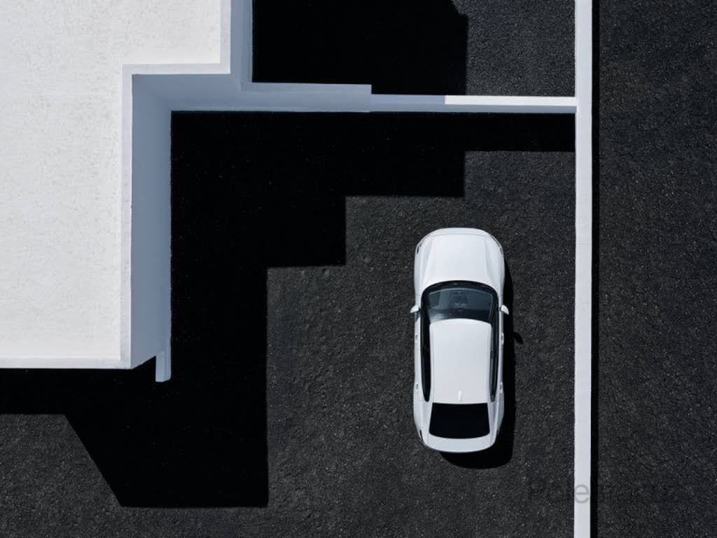 Белый Polestar 2 сверху, припаркованный рядом с белым зданием